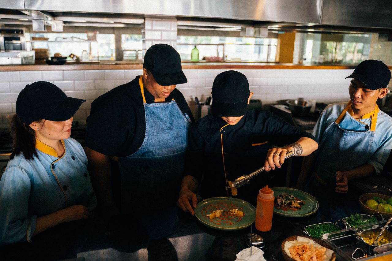 Trainees preparing and plating food in a professional commercial kitchen